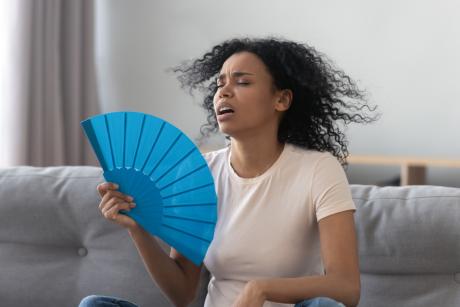 女人在家里给自己扇风，炎热的夏天
